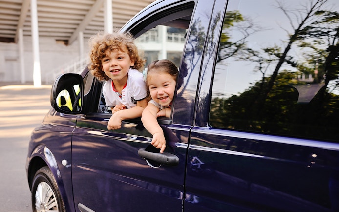 Children smiling from a car window during a Cinque Terre tour from Florence.