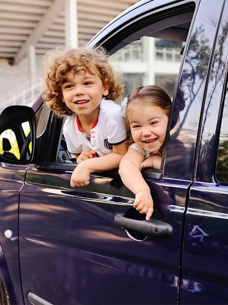 Children smiling from a car window during a Cinque Terre tour from Florence.