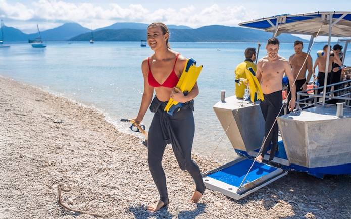 Tourists disembarking from a boat after snorkeling at Fitzroy Island beach.
