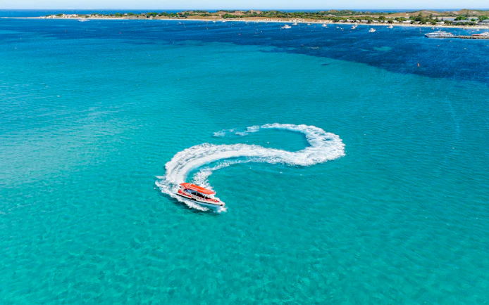 Red boat making a 360-degree turn, creating a white wake in turquoise water.