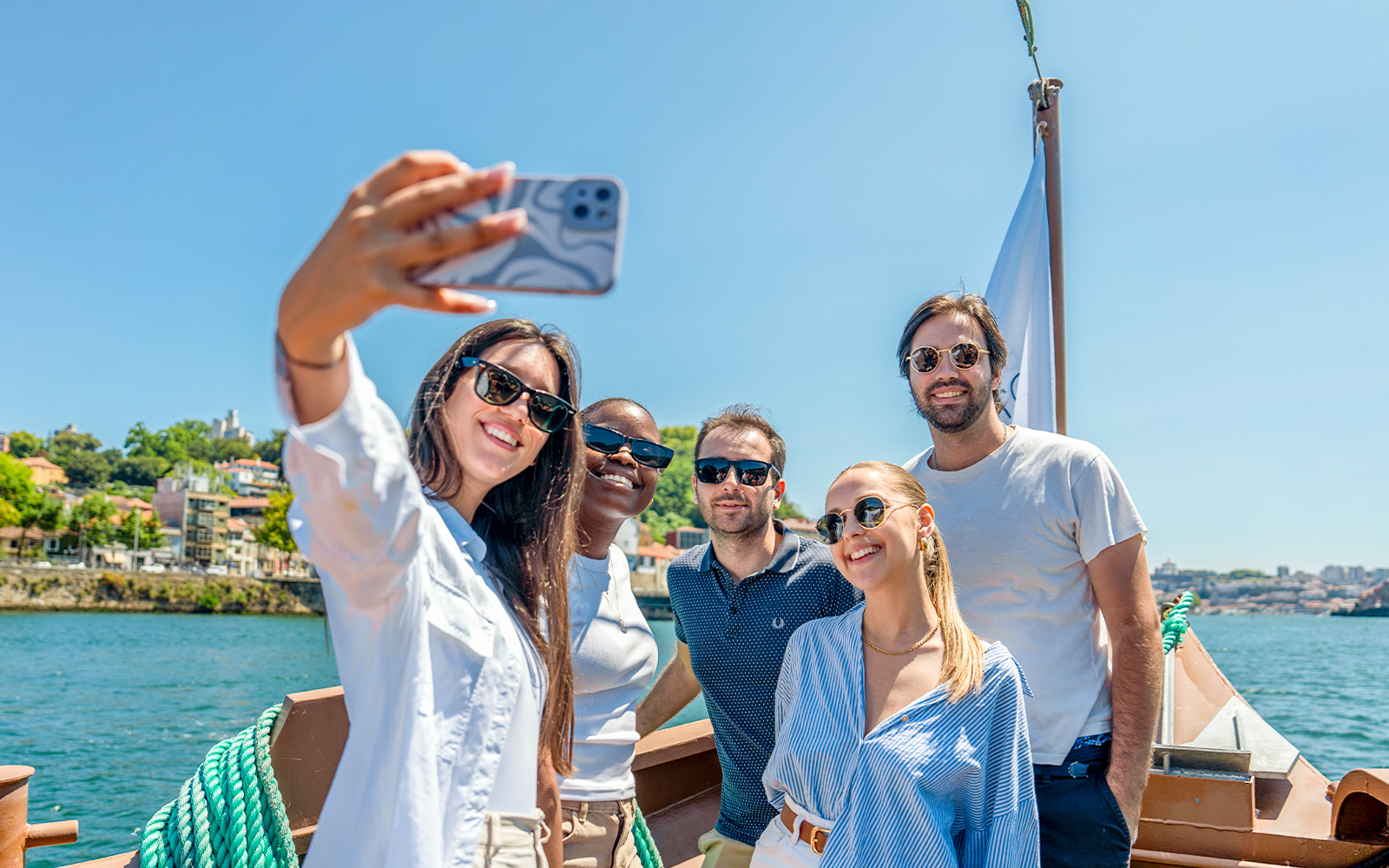 Tourists taking selfies on a Douro River cruise with scenic views of Porto.