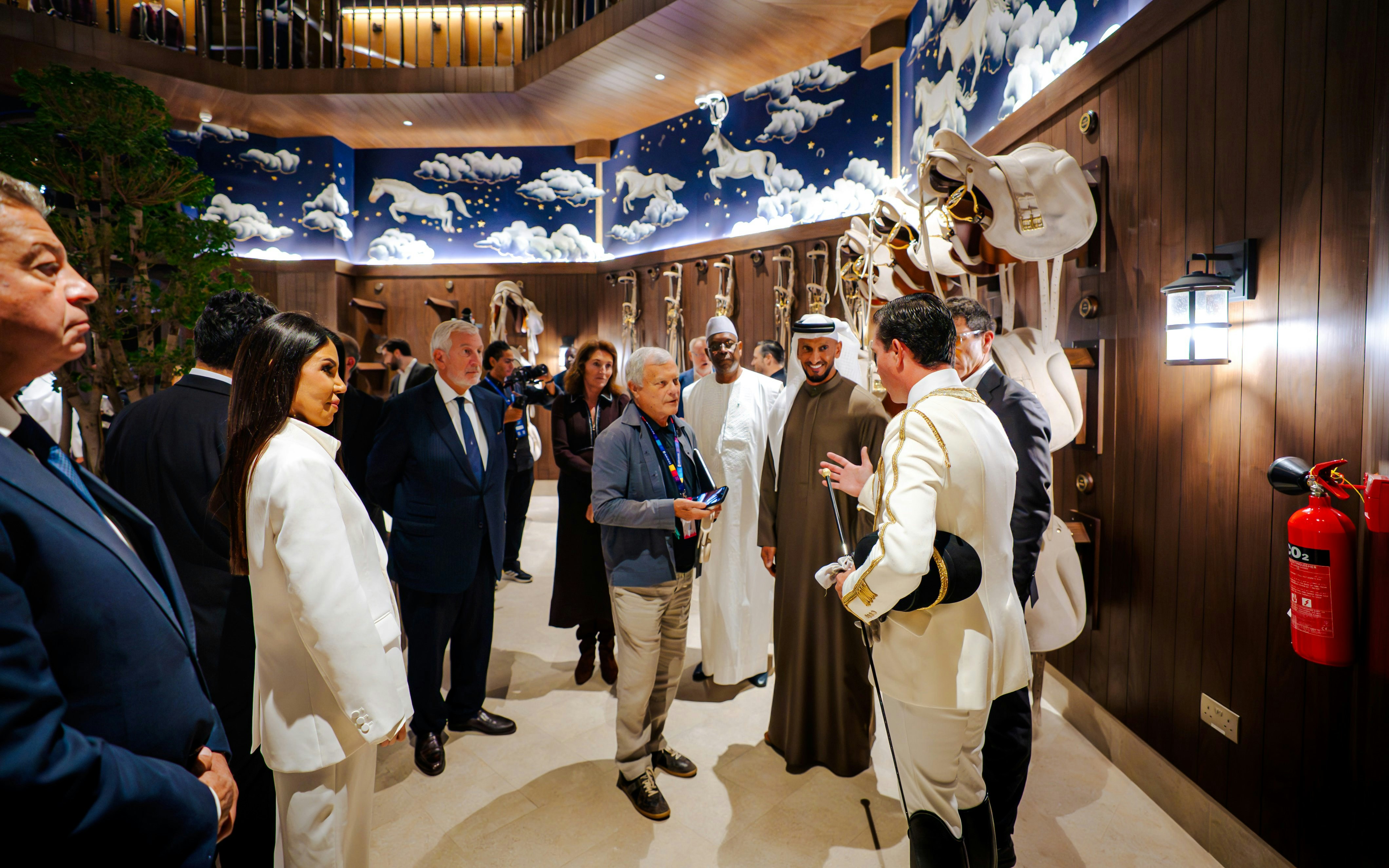 Group touring Abu Dhabi Royal Equestrian Arts venue with horse-themed decor.