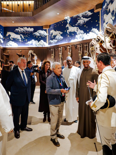 Group touring Abu Dhabi Royal Equestrian Arts venue with horse-themed decor.