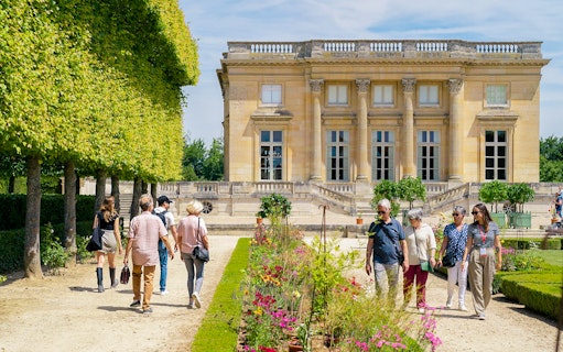 Tourists with guide exploring gardens at Petit Trianon, Versailles.