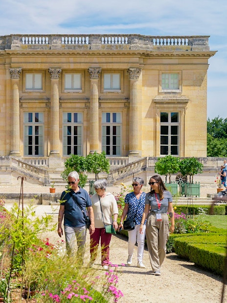 Tourists with guide exploring gardens at Petit Trianon, Versailles.