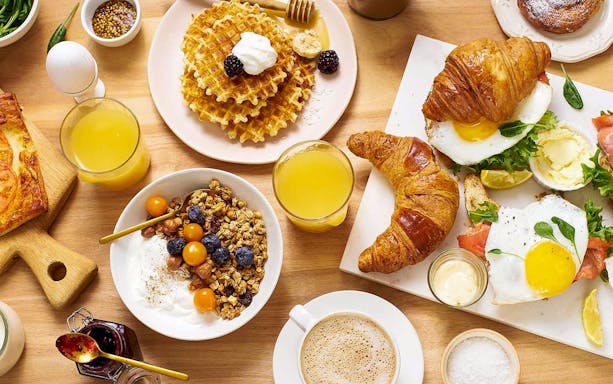 Sunday brunch spread with waffles, croissants, eggs, granola, and juice for Danube sightseeing cruise.
