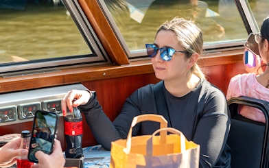 Person enjoying a drink on an Amsterdam canal cruise boat.