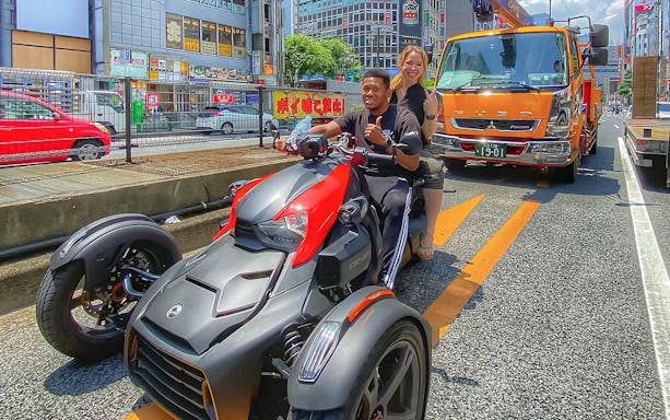 Go-kart riders on Tokyo street with cityscape backdrop.