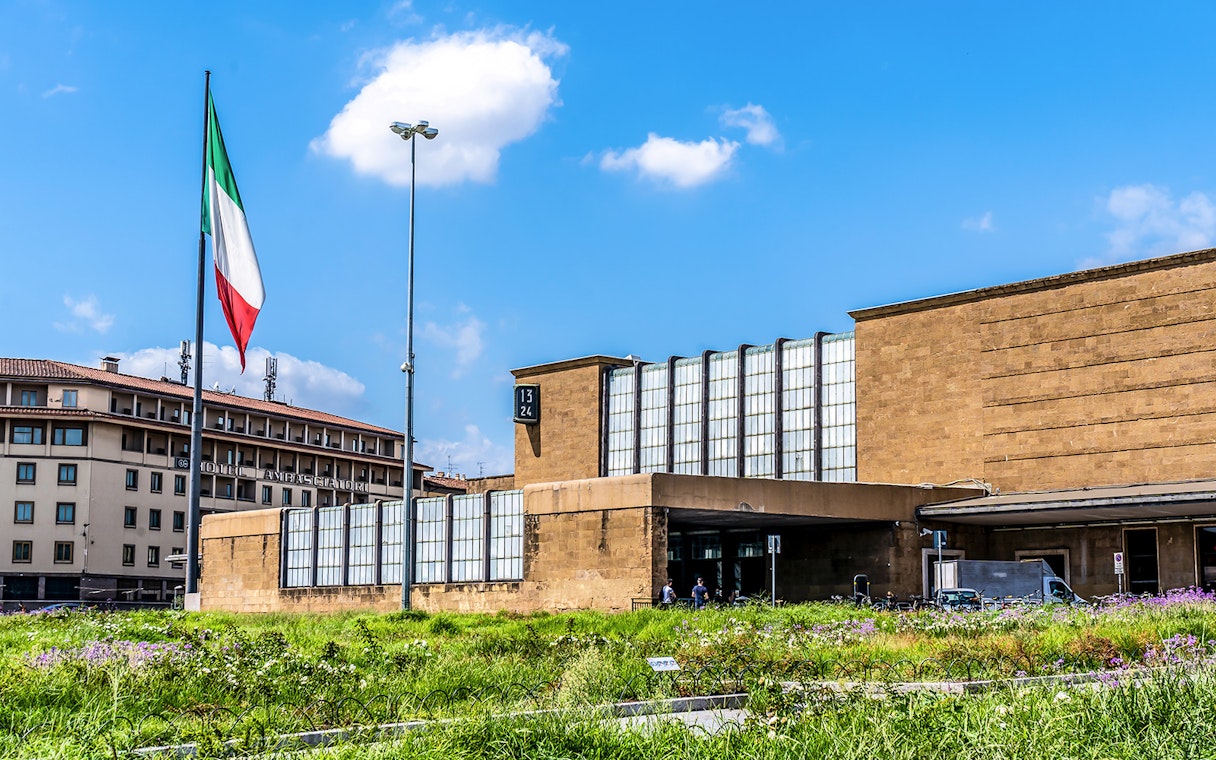 Florence Santa Maria Novella Station with Italian flag and surrounding buildings.