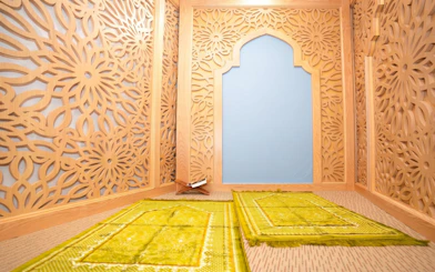 Prayer room with intricate wooden lattice design and green prayer mats at Jasmine Halal Lounge, Tan Son Nhat Airport.