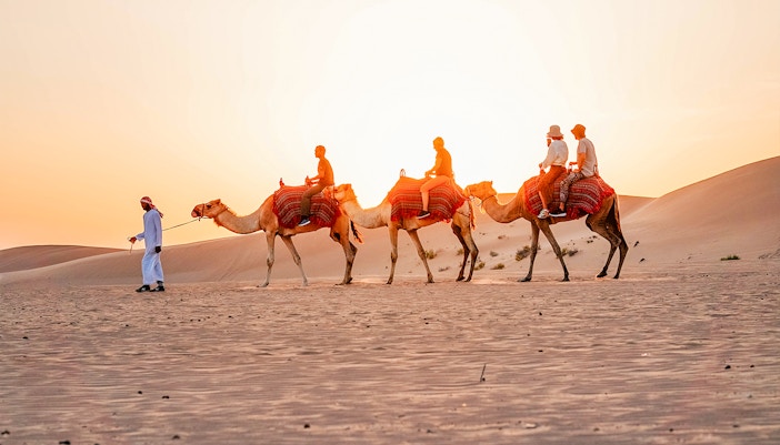 Camel ride during evening desert safari in Abu Dhabi with BBQ dinner experience.