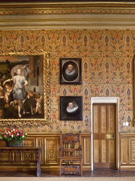 Chenonceau Castle interior with ornate paintings and floral wallpaper.