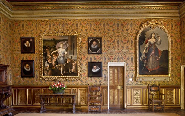 Chenonceau Castle interior with ornate paintings and floral wallpaper.