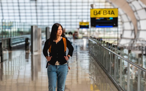 Traveler walking through Bangkok Suvarnabhumi Airport terminal.