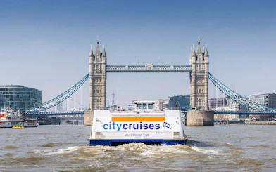 City cruise boat on Thames River with Tower Bridge in the background, London.