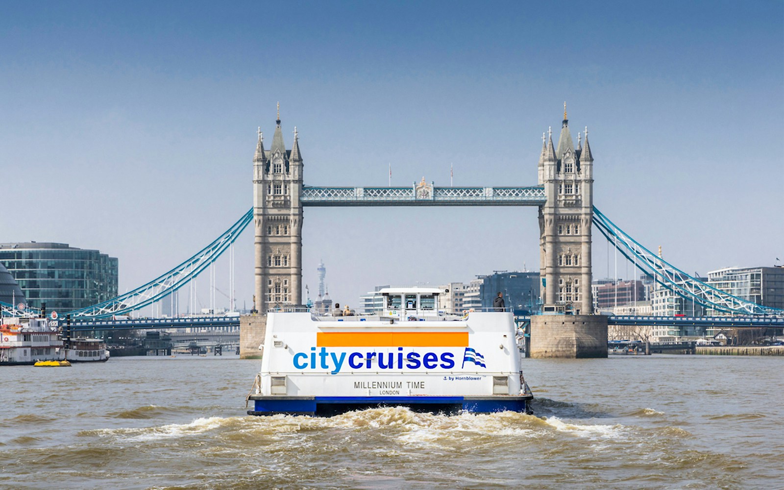 City cruise boat on Thames River with Tower Bridge in the background, London.