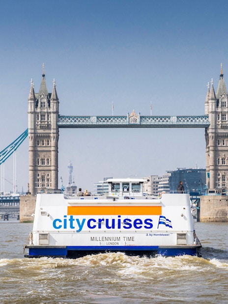 City cruise boat on Thames River with Tower Bridge in the background, London.