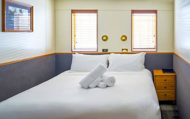 Cruise cabin with bed and towels for Milford Sound overnight tour.