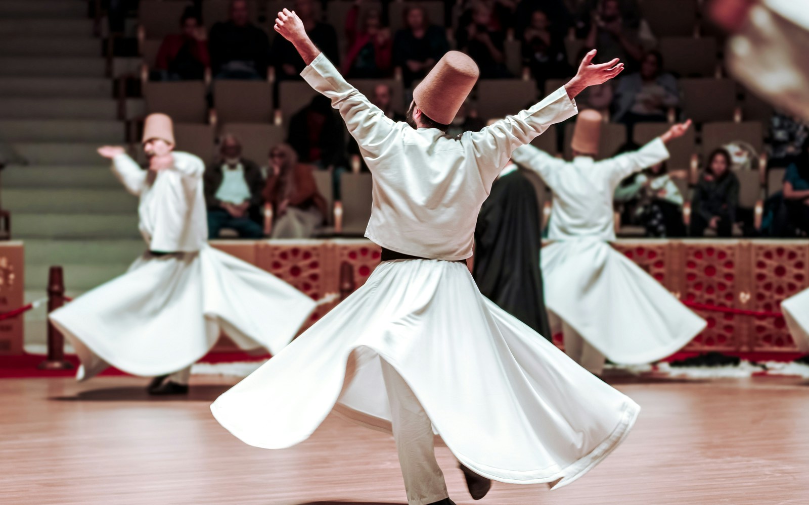 Whirling Dervishes performing in a historic venue with an audience in Istanbul.