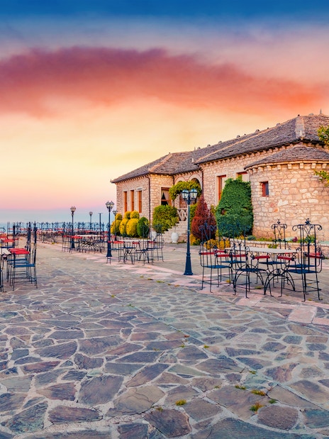 Lekursi Castle terrace with empty tables at sunset, overlooking the sea.