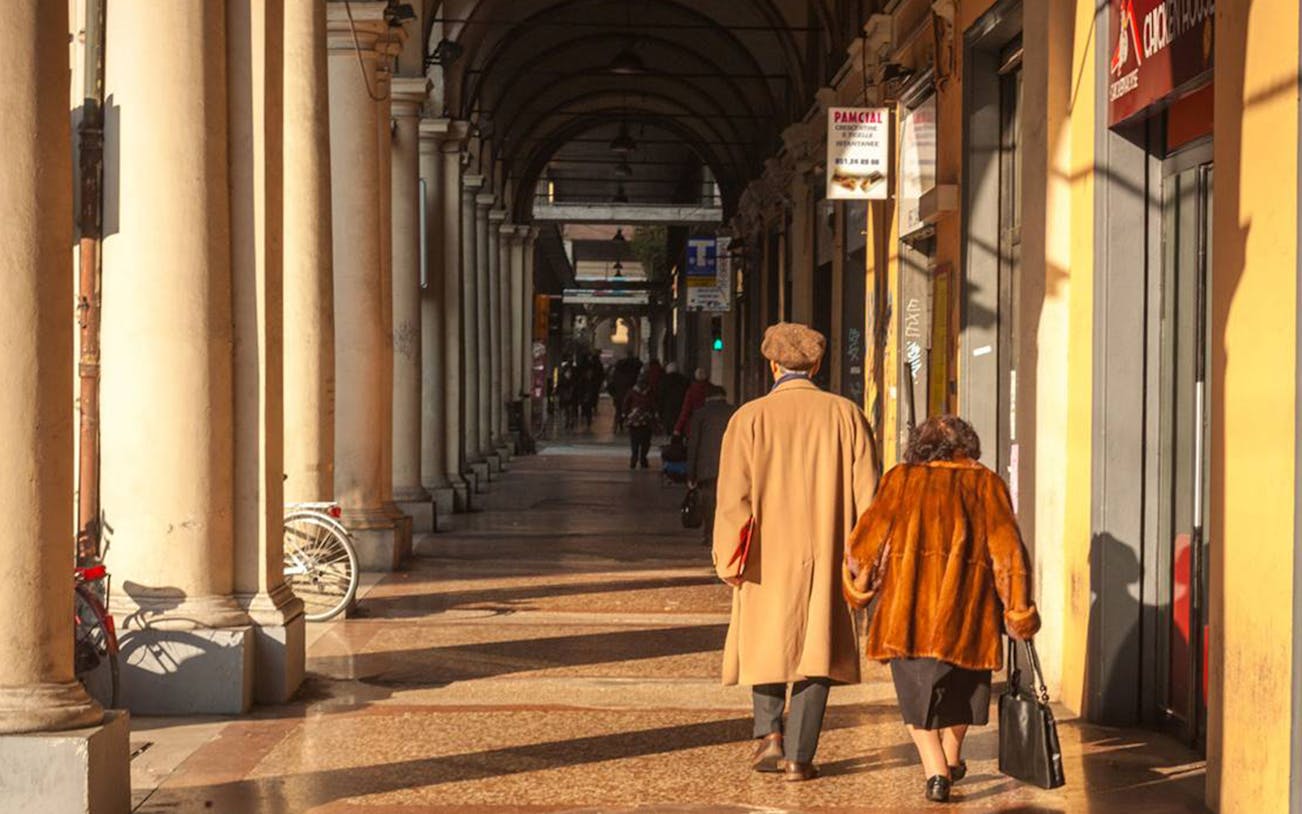 Couple walking under Bologna's historic porticoes during a 3-hour tasting tour.
