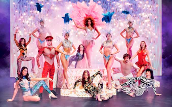 Paradis Latin show performers in vibrant costumes on stage with dinner setting.