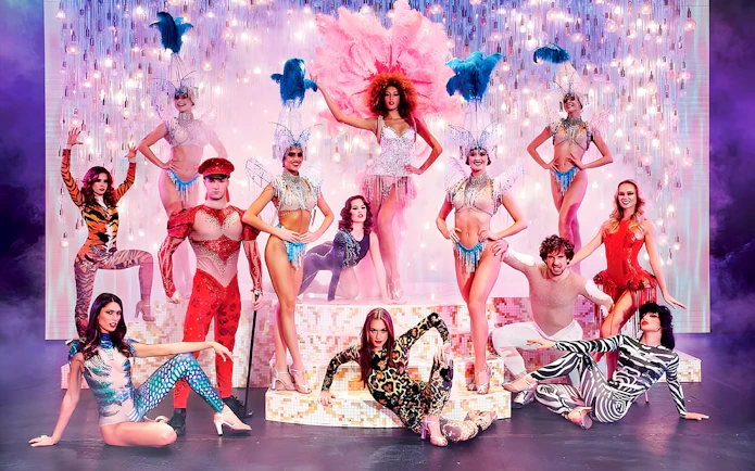 Paradis Latin show performers in vibrant costumes on stage with dinner setting.