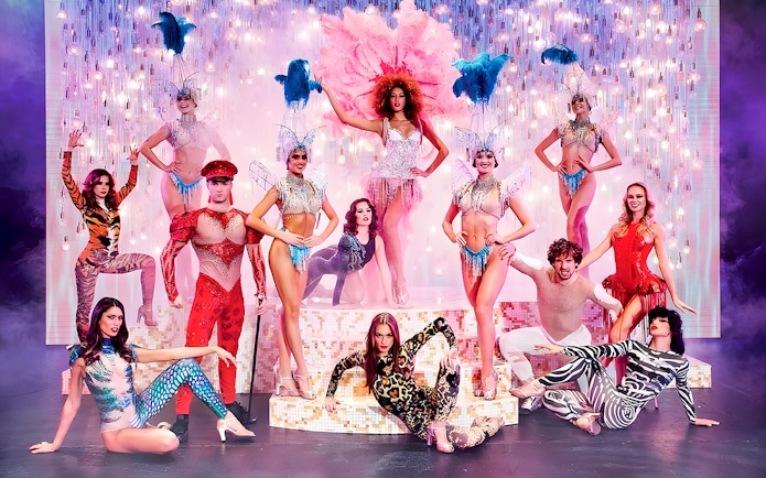 Paradis Latin show performers in vibrant costumes on stage with dinner setting.