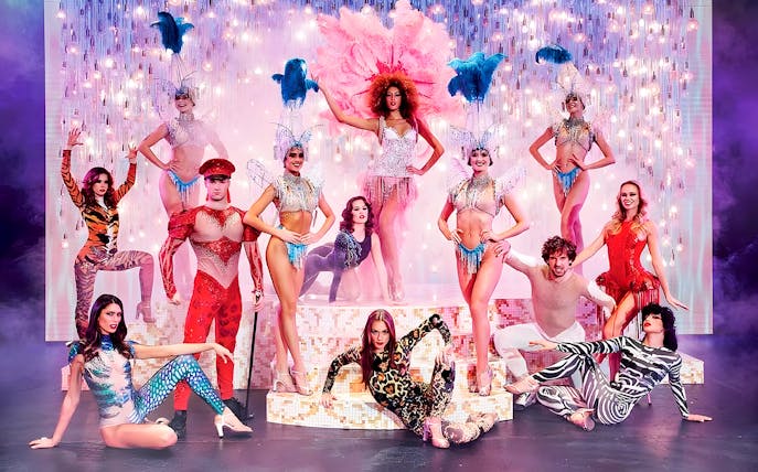 Paradis Latin show performers in vibrant costumes on stage with dinner setting.