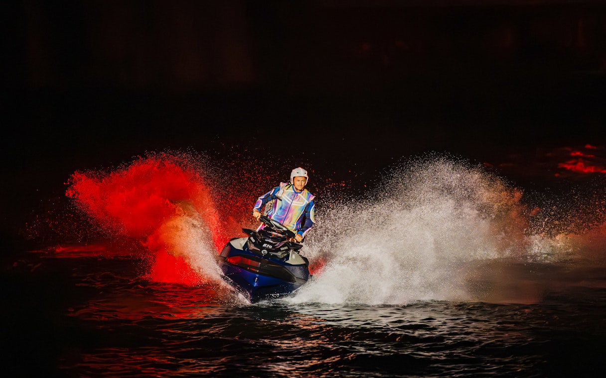 Performer doing Jet Ski stunts at Symphony of the Sea show with dramatic water spray.