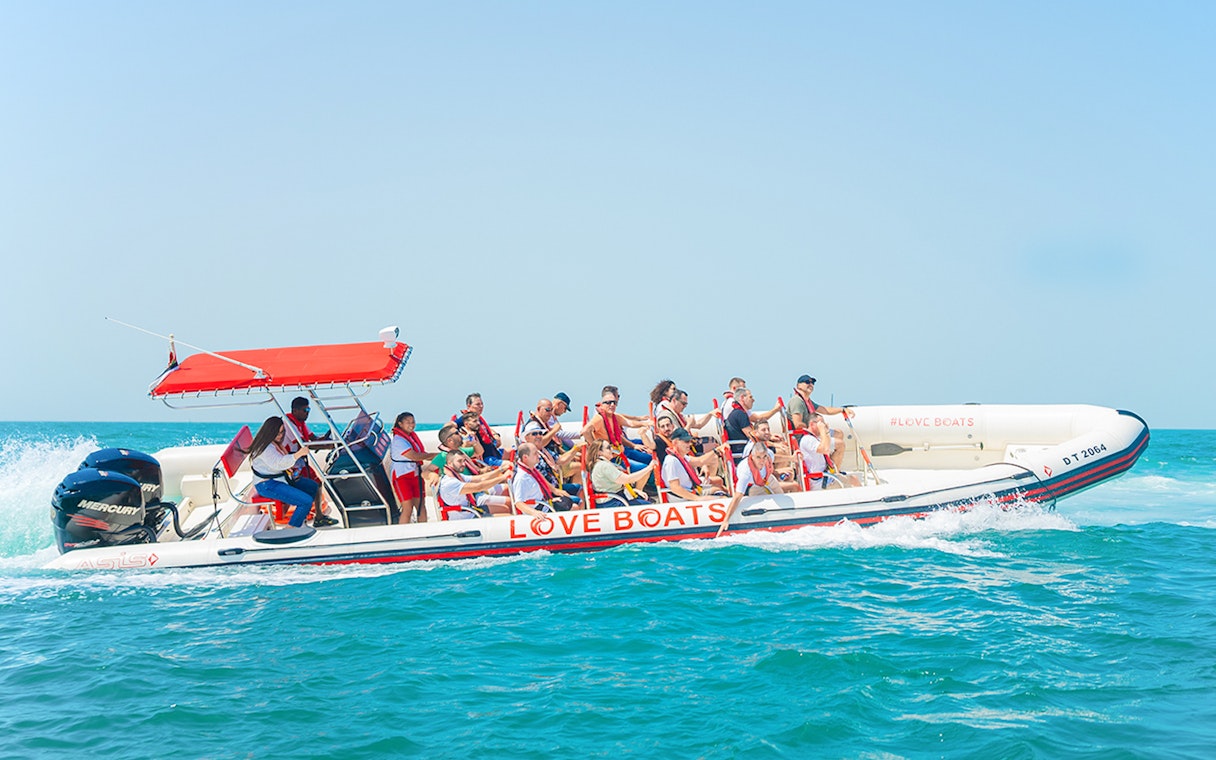 Tourists enjoying a Love Boats marina tour on a speedboat in clear blue waters.