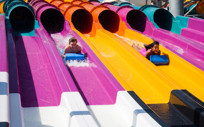 Riders on colorful water slides at Wahoo Racer, Hurricane Harbor Arlington.