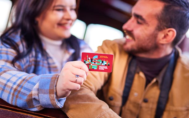 Couple holding Prague Visitor Pass on public transport.