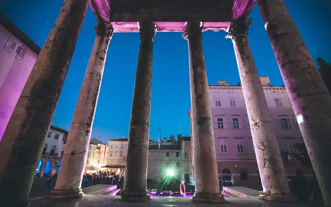 Ancient columns of a temple in Pula at dusk during a city exploration game.