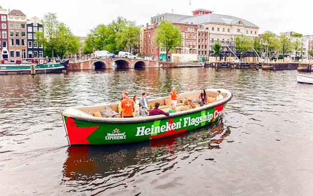 Tourists on Heineken Experience cruise boat in Amsterdam canal.