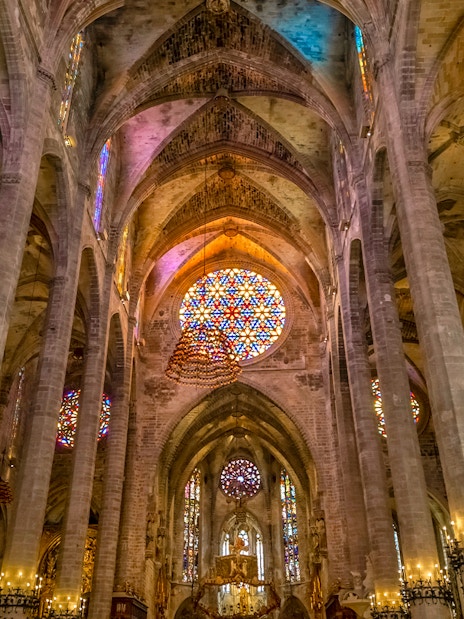 Gothic interior with stained glass windows and columns in Palma Cathedral.