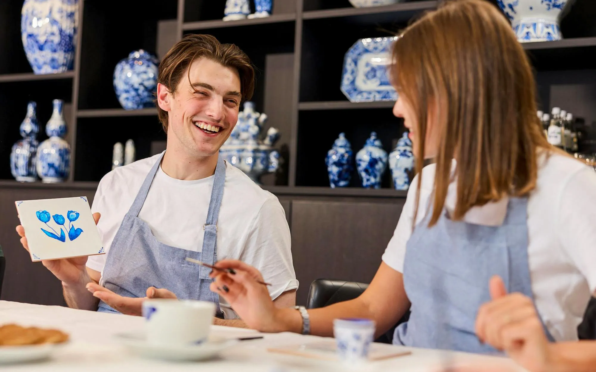 Guests painting tiles at a Dutch blue tile workshop, showcasing tulip design.