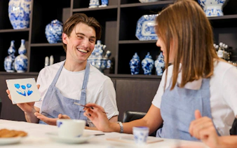 Guests painting tiles at a Dutch blue tile workshop, showcasing tulip design.