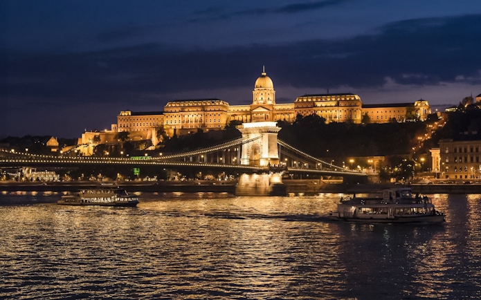 Buda Castle and Chain Bridge illuminated at night during a Danube sightseeing dinner cruise.