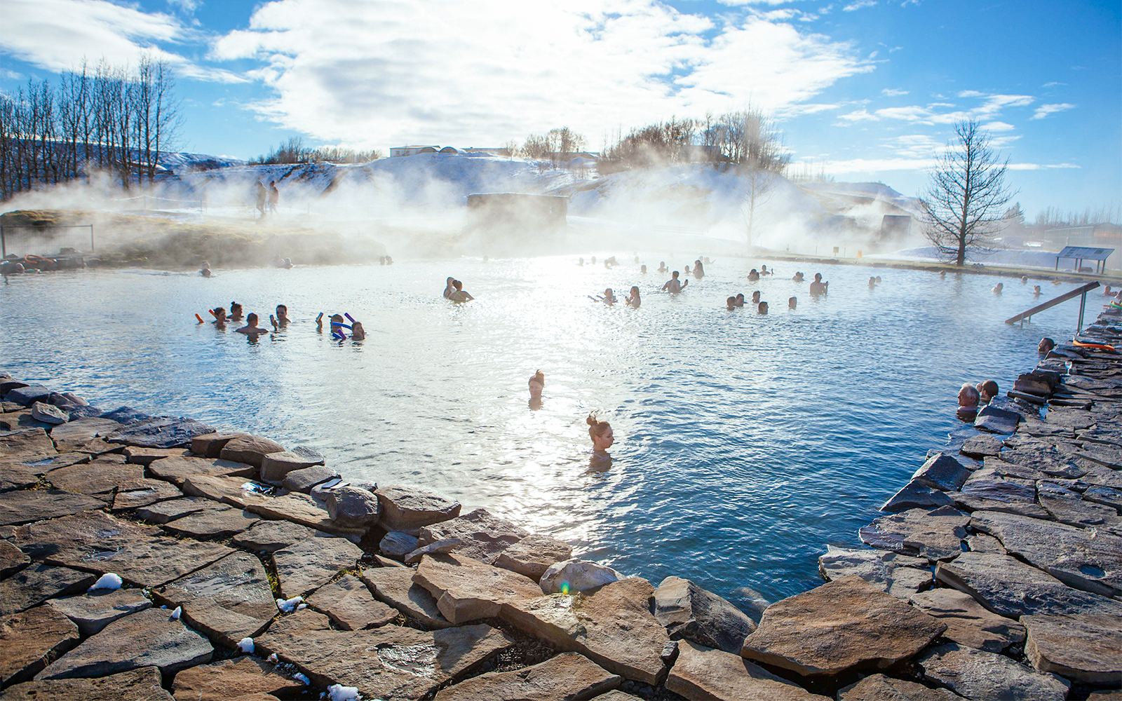 People enjoying the geothermal waters of Secret Lagoon in winter, Iceland.
