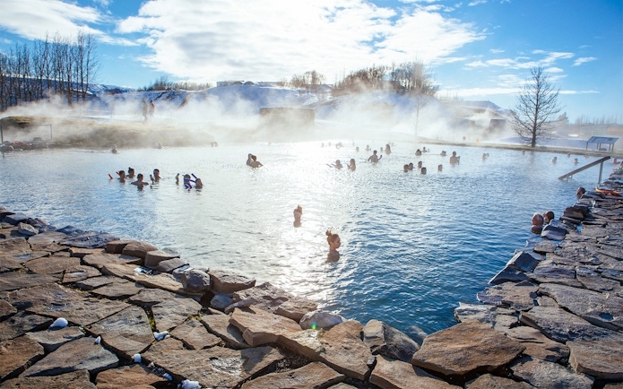 People enjoying the geothermal waters of Secret Lagoon in winter, Iceland.