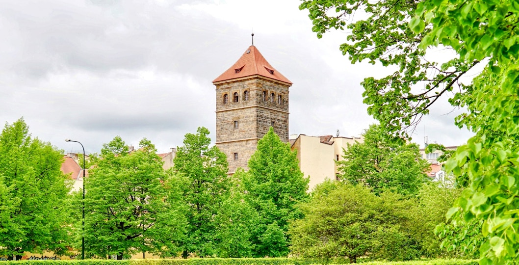 New Mill Water Tower in Prague surrounded by lush green trees.