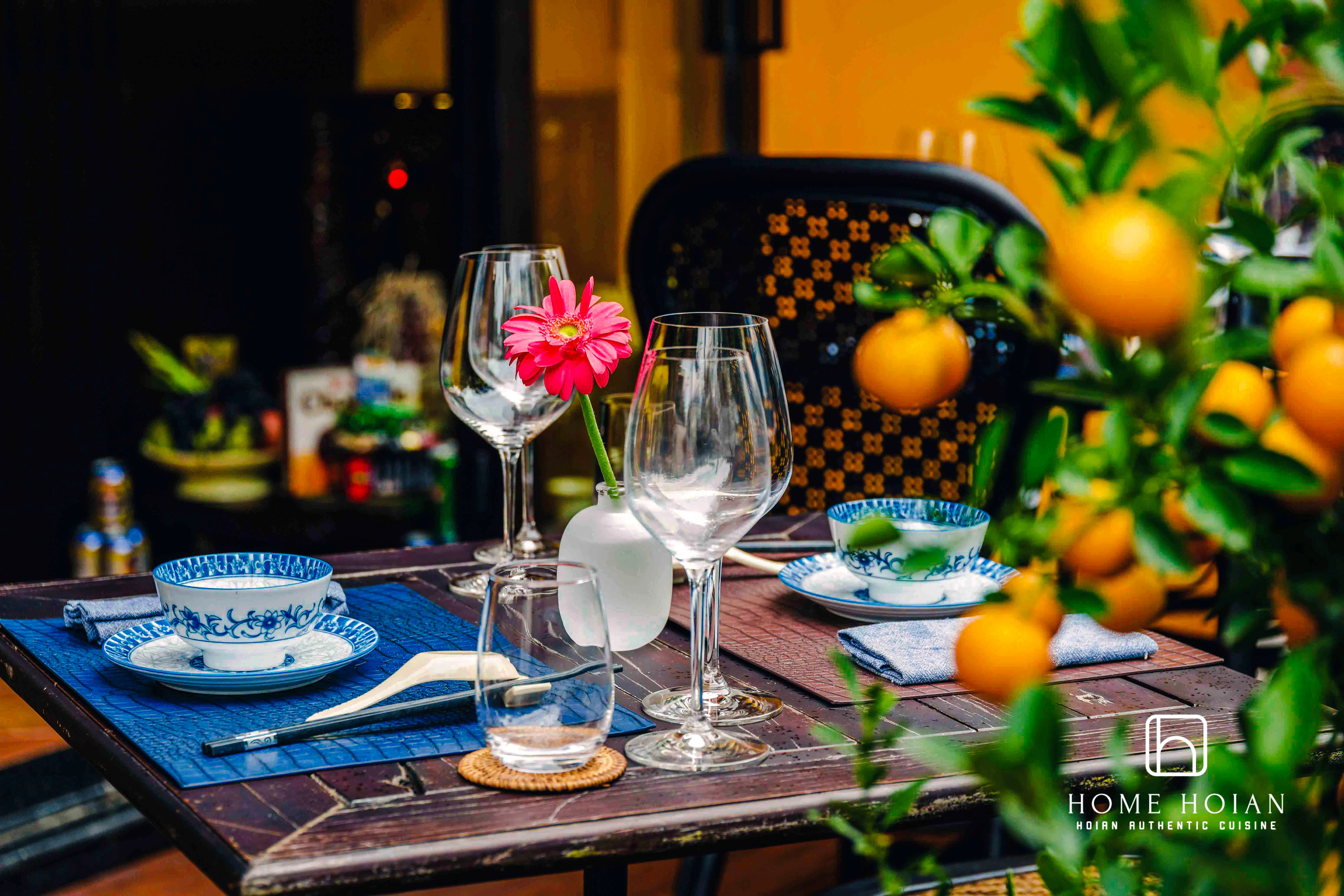 Dining table set with blue-patterned dishes and glassware at HOME Hoi An Restaurant, Vietnam.