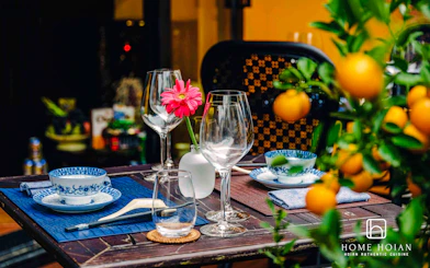 Dining table set with blue-patterned dishes and glassware at HOME Hoi An Restaurant, Vietnam.