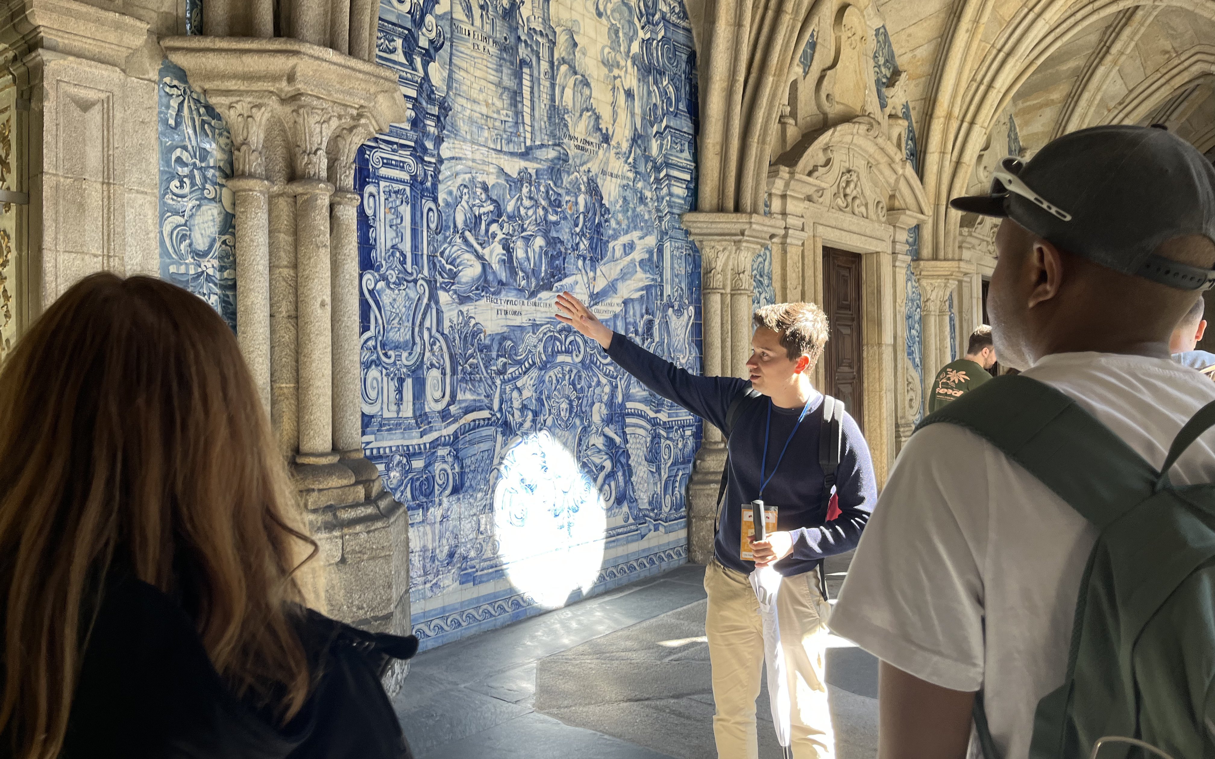 Tourist group on guided tour inside Porto Cathedral, Portugal, viewing blue azulejo tiles.