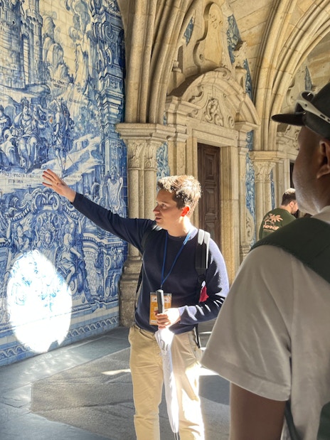 Tourist group on guided tour inside Porto Cathedral, Portugal, viewing blue azulejo tiles.