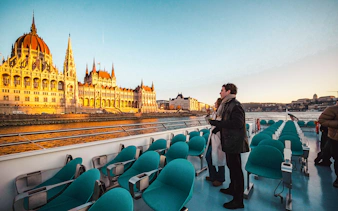 Guests enjoying Budapest Sunset Cruise with view of Hungarian Parliament Building.