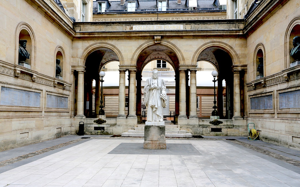 Statue in the courtyard of Collège de France, Paris, framed by arches and classical architecture.