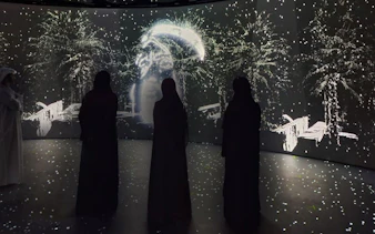 Visitors observing digital art display at Diya Experience, Sheikh Zayed Grand Mosque Centre.