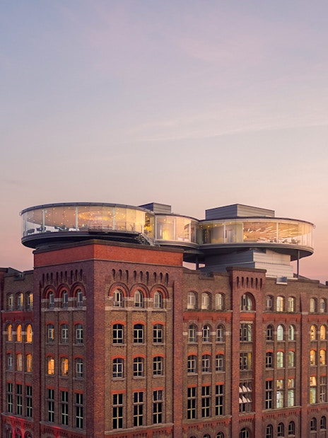 Guinness Storehouse exterior with glass rooftop at sunset in Dublin, Ireland.
